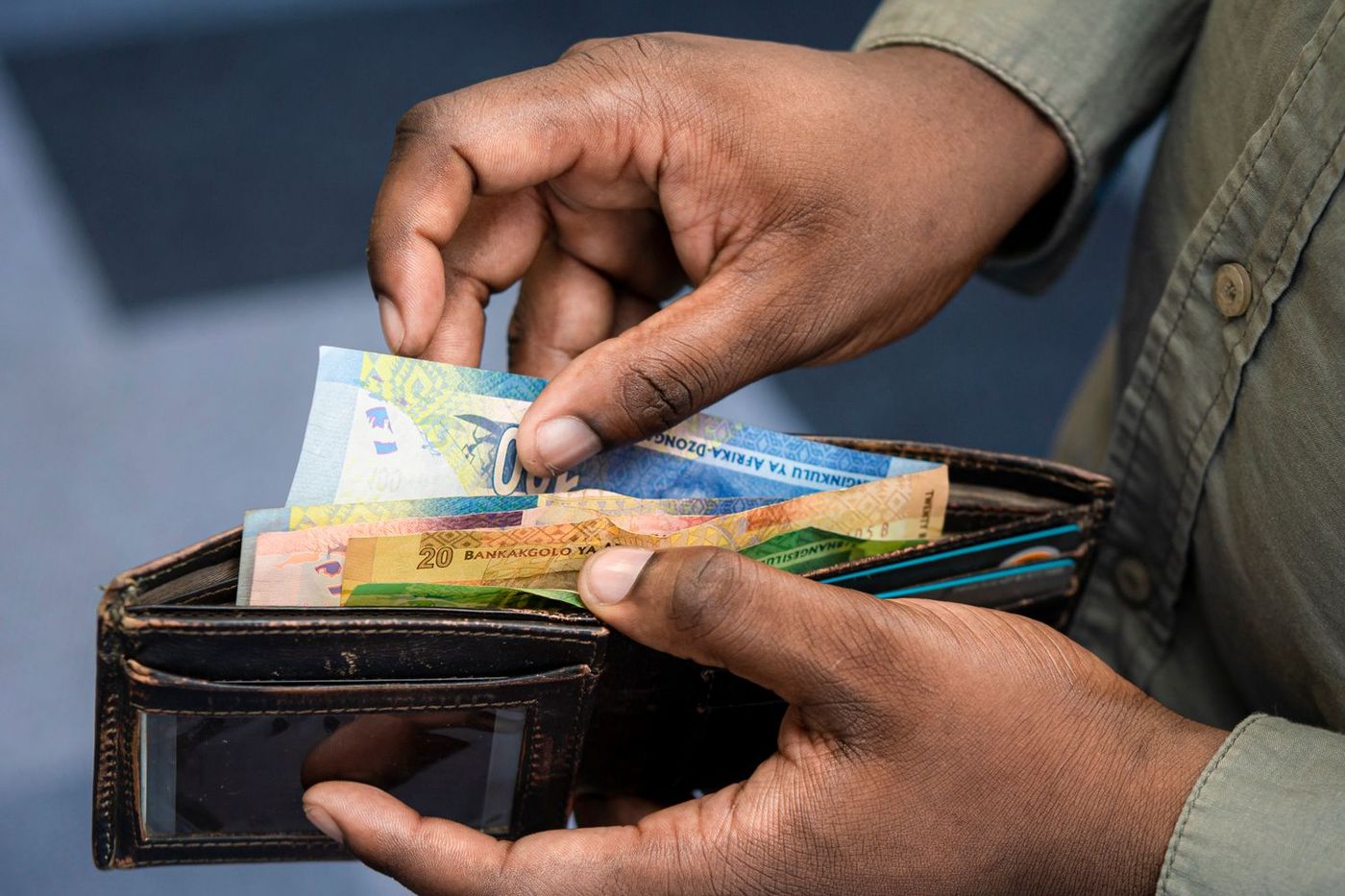 Hands counting banknotes from a worn leather wallet